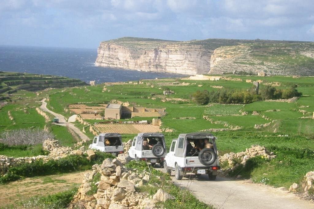 Passengers in an open jeep looking out over Gozo.